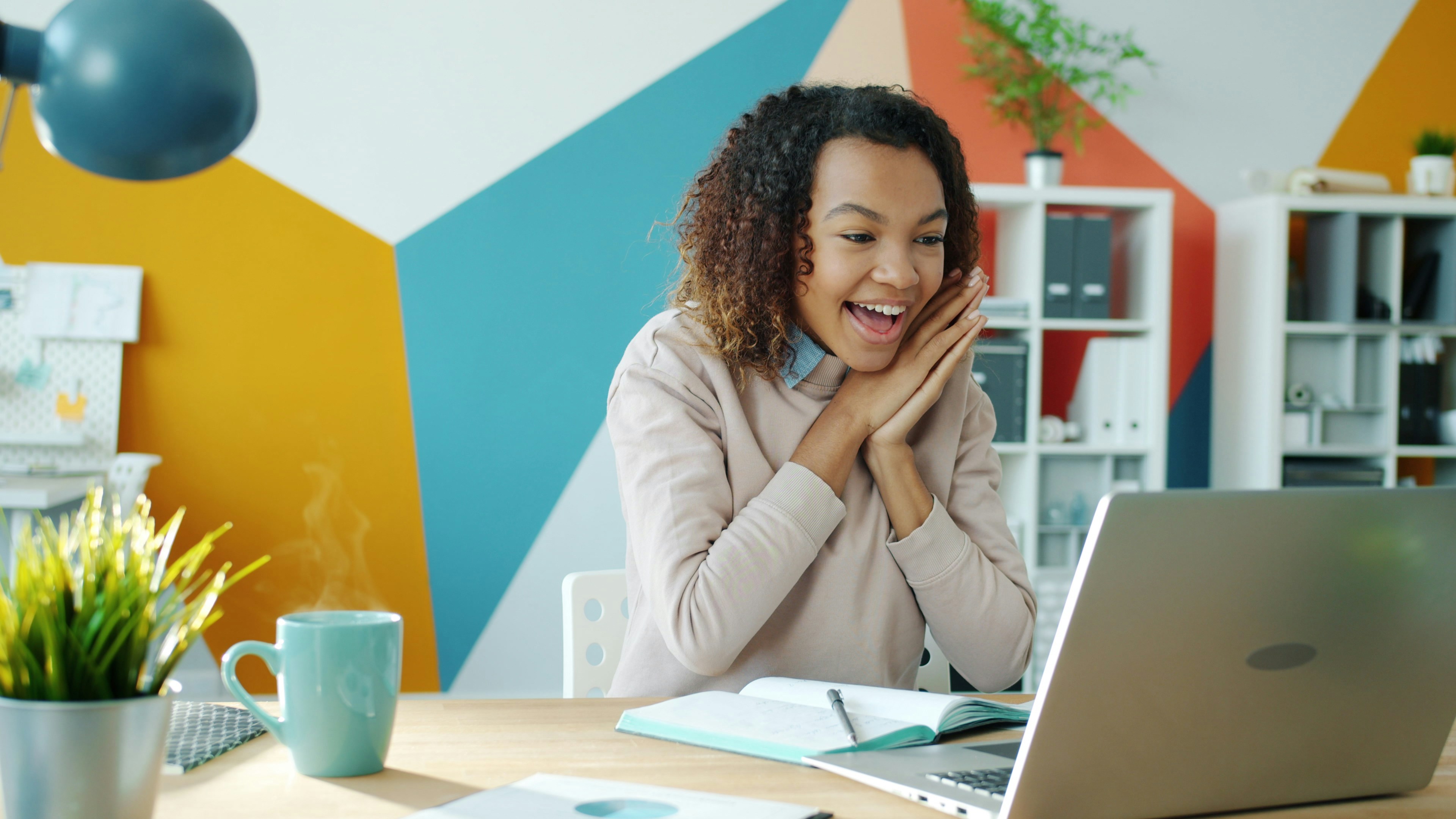 Woman pleasantly surprised looking at her laptop screen