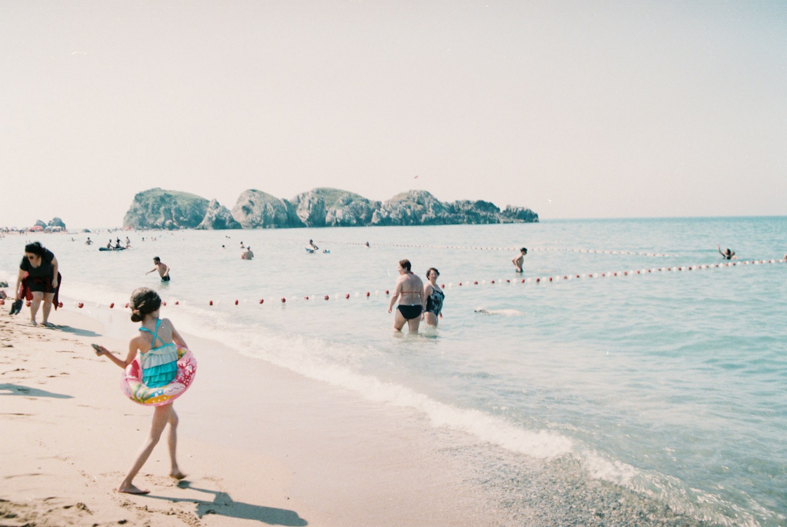 People swimming at a sunny beach on a summer vacation day